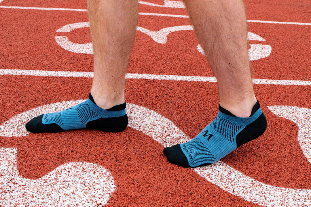 A person walking on a track in Wrightsock Grey Racer Tab socks.